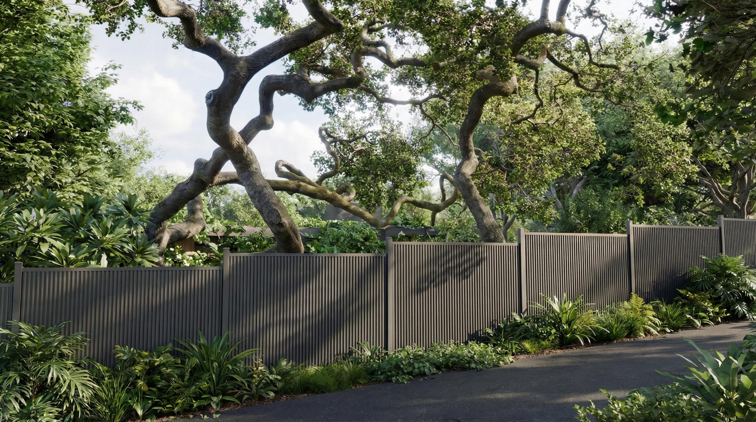 Dark gray vertical-slat steel privacy fence bordering a landscaped garden path beneath mature trees and dense greenery.